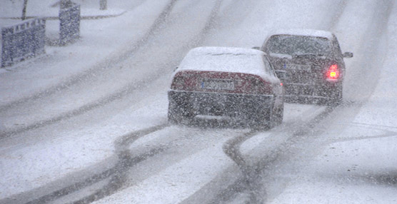 Automóviles circulando por una carretera nevada.