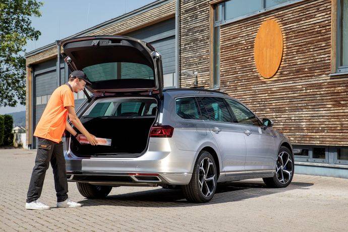 Un mensajero de Nacex deposita un paquete en el maletero de un Volkswagen Passat. 