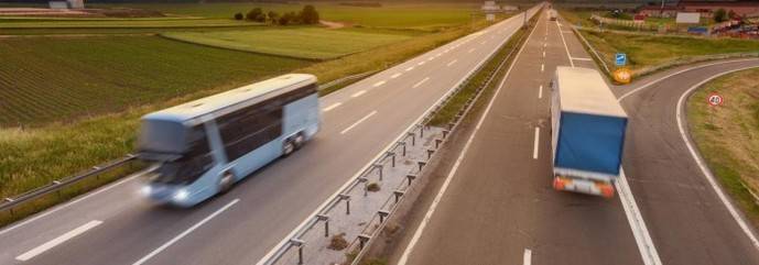 Un autocar y un camión circulan por una autopista.