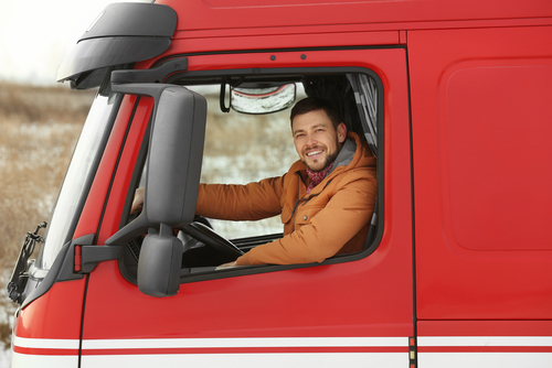 Camionero sonriente al volante de su vehículo.