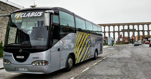 Un autocar en la ciudad de Segovia, con el acueducto de fondo.